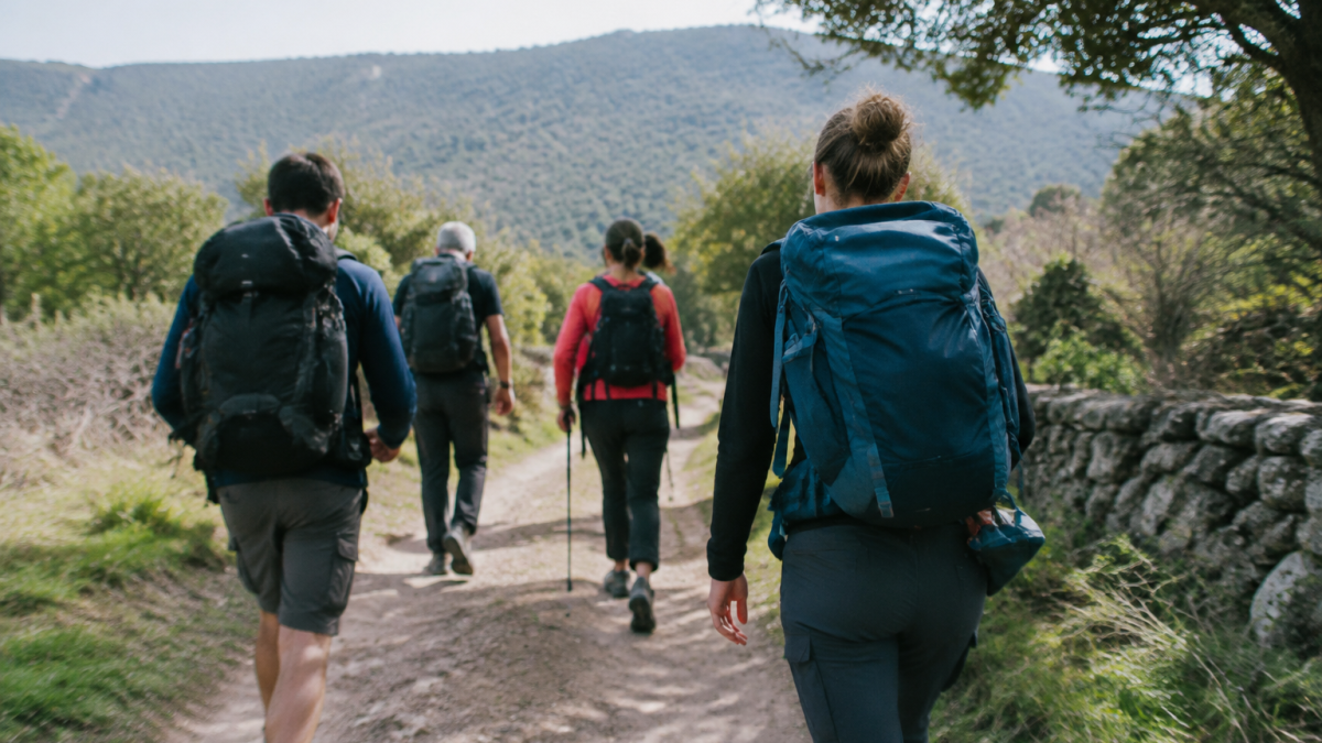 Marcheurs avec sacs progressent sur piste de terre