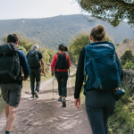 Marcheurs avec sacs progressent sur piste de terre