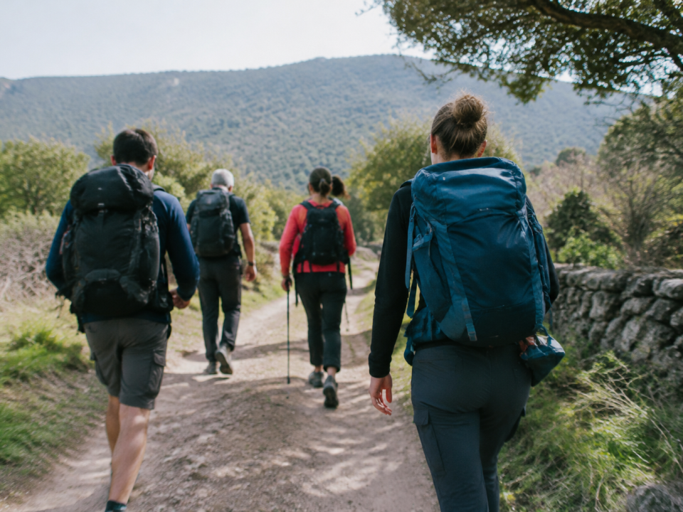 Marcheurs avec sacs progressent sur piste de terre
