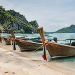 Bateaux longtail en bois alignés sur sable blanc