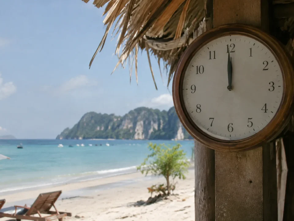 Une horloge murale affiche midi devant une plage thailandaise