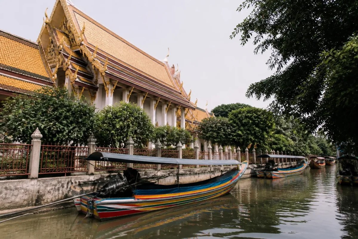 Temple aux toits dores et barques colorees sur canal