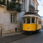 Tram jaune traversant une rue pavee du quartier Alfama