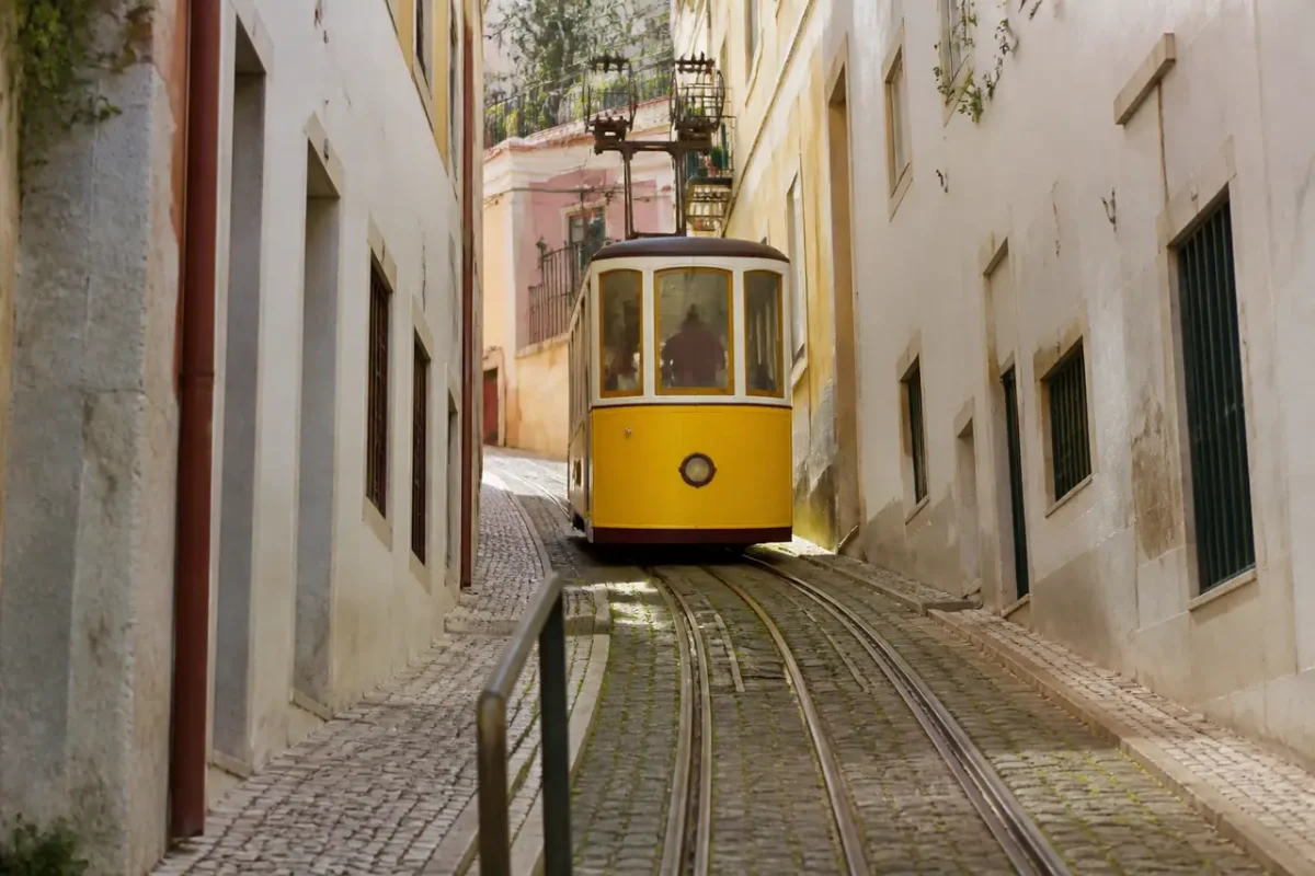 Tramway jaune grimpant une ruelle pavee au soleil